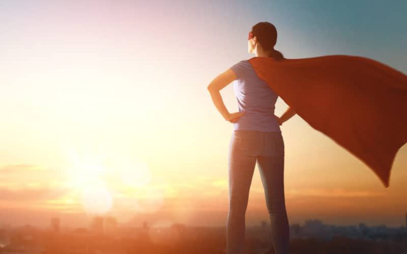 Woman with a superhero cape on top of a mountain